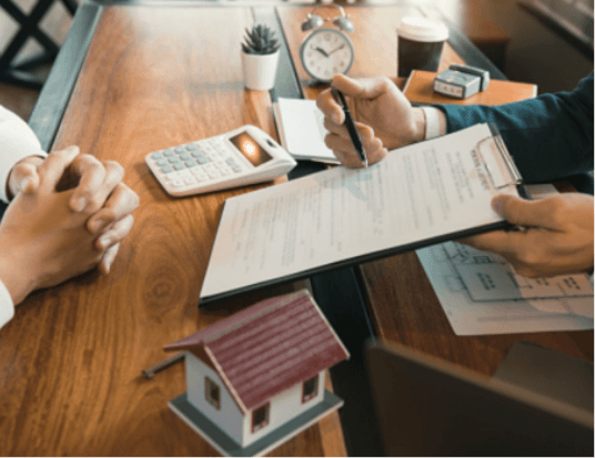 Advisor showing their client a loan contract at their desk on a clipboard.